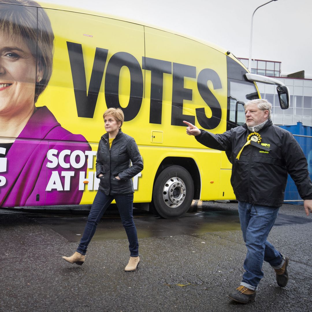 Scottish National Party (SNP) leader Nicola Sturgeon walks past her campaign bus with SNP candidate Angus Robertson in Edinburgh on May 4, 2021. 