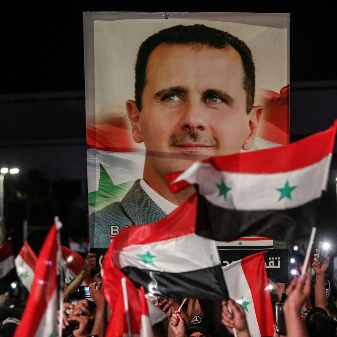 Syrians wave national flags and carry a large portrait of President Bashar al Assad in the streets of Damascus on May 27, 2021.