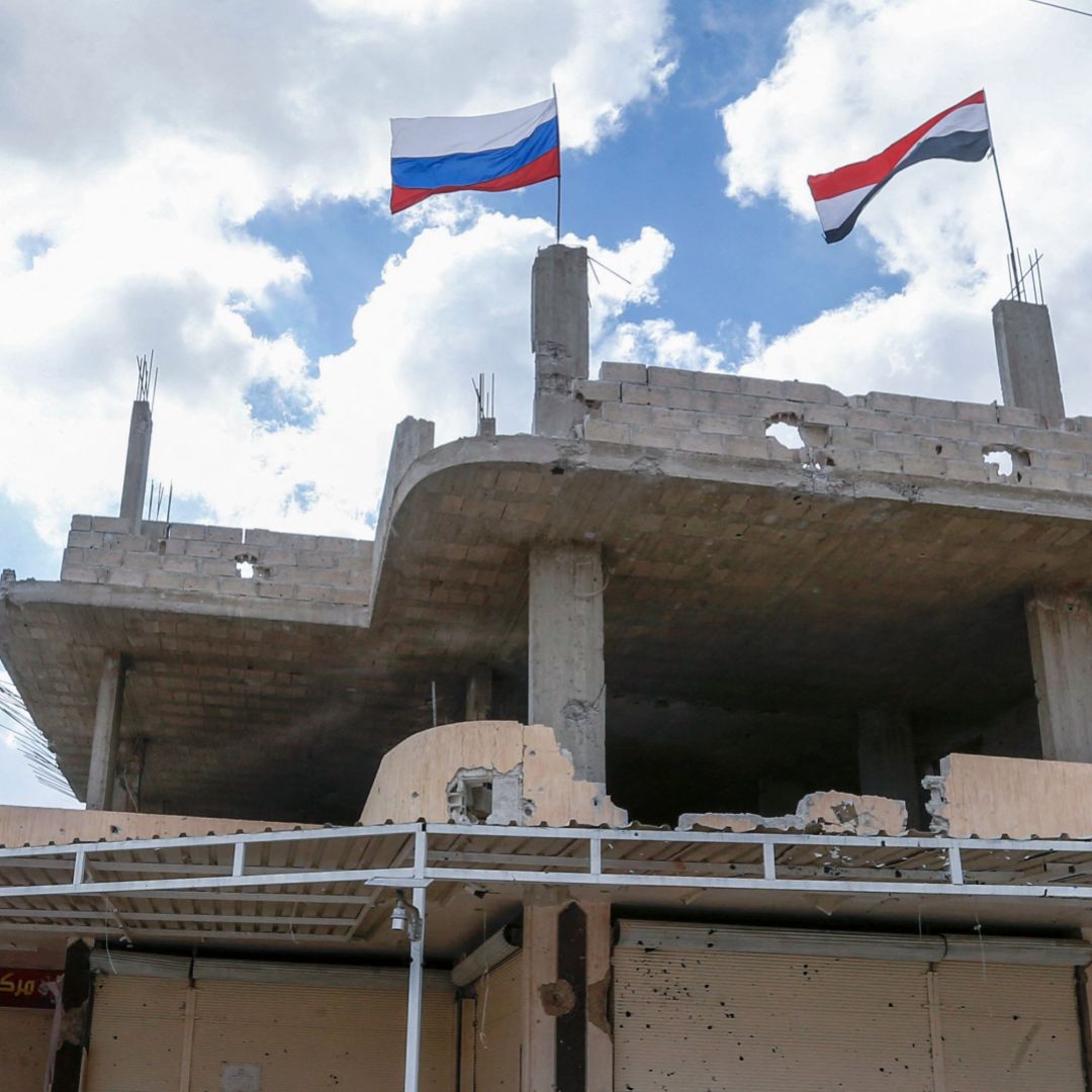 Russian and Syrian flags wave above a damaged building in Syria's southern city of Daraa on Sept. 12, 2021.