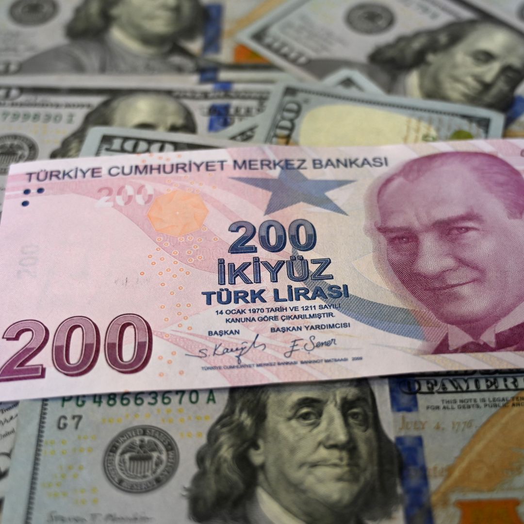 A Turkish lira banknote is seen on top of U.S. dollar banknotes in Istanbul, Turkey, on Dec. 7, 2021. 