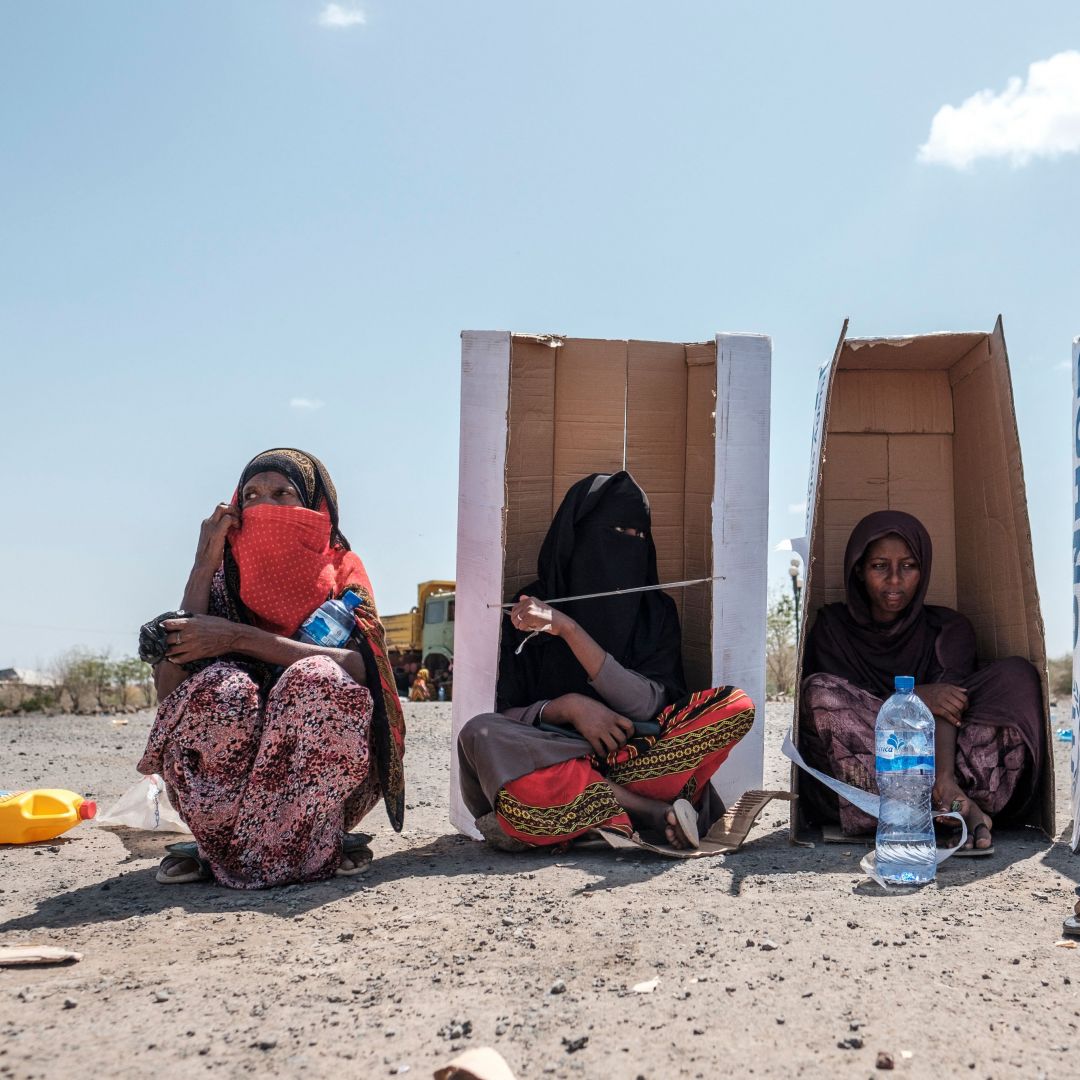 Women sit under U.N.-branded cardboard boxes in Semera, Ethiopia, on Feb. 14, 2022, as they wait to be registered by the authorities at a hotel compound hosting civilians fleeing violence. 