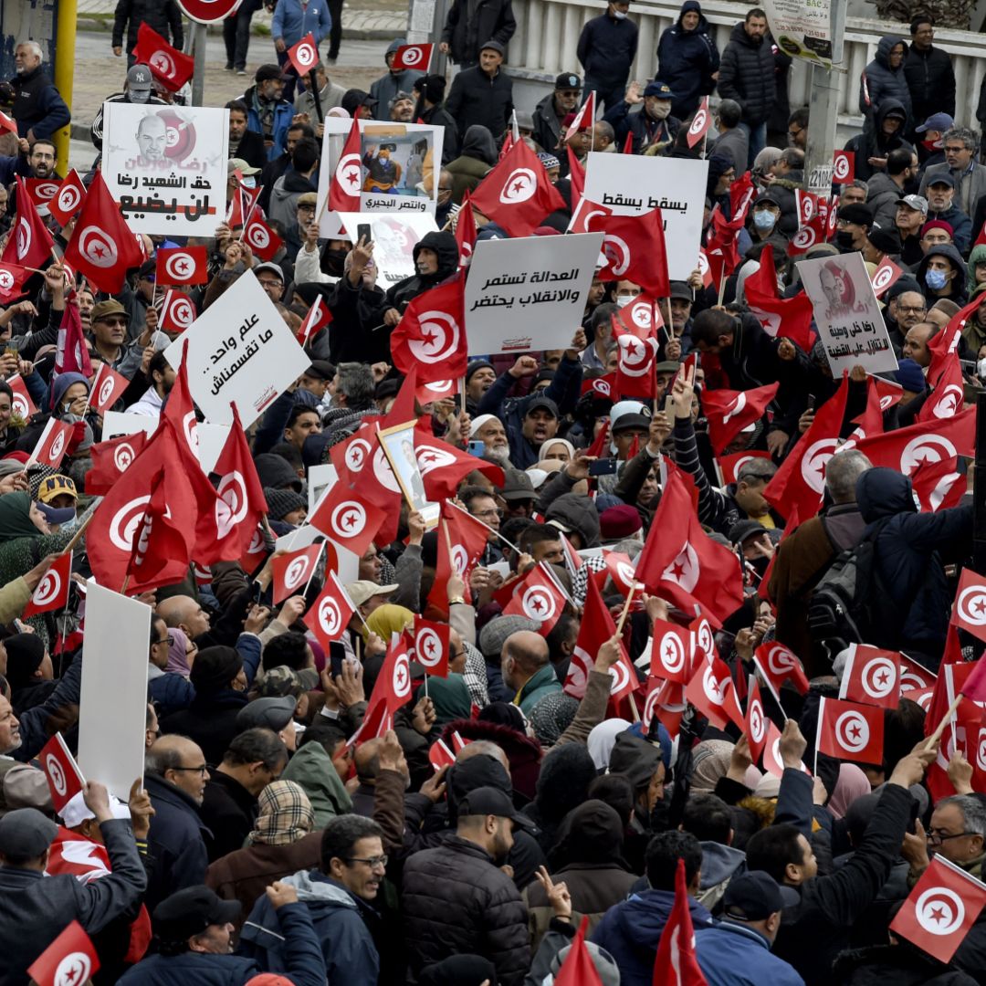 Tunisian protesters raise national flags during a demonstration against their president in the capital of Tunis on March 20, 2022. 