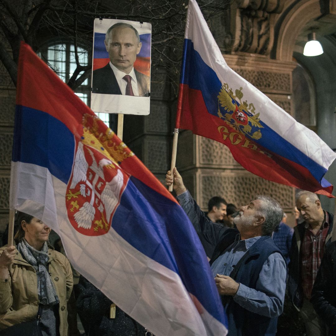 Demonstrators in Belgrade, Serbia, hold up Serbian flags and a photo of Russian President Vladimir Putin on March 24, 2022, during a rally in support of the Russian invasion of Ukraine. 