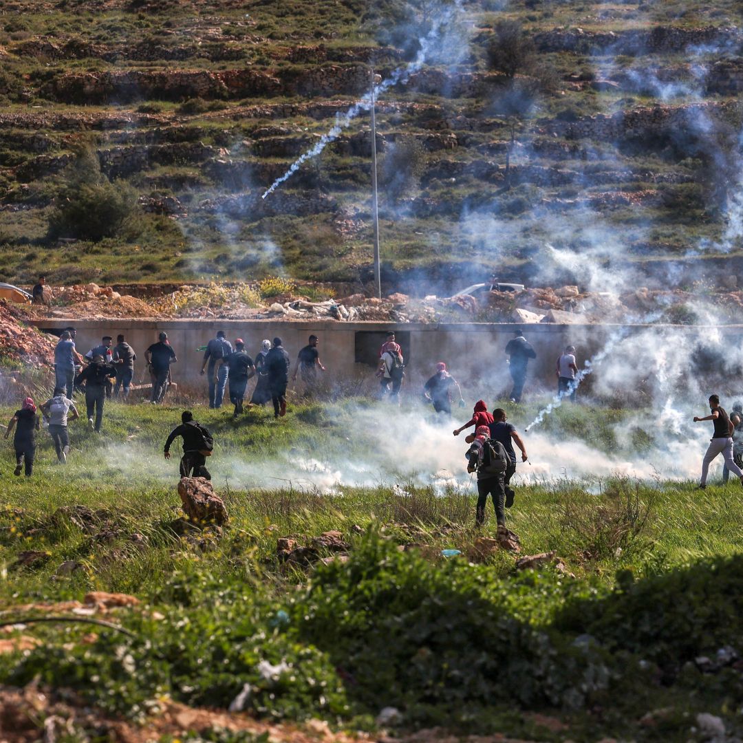 Palestinians run for cover during clashes with Israeli security forces near the Israeli settlement of Beit El in the occupied West Bank on April 11, 2022. 