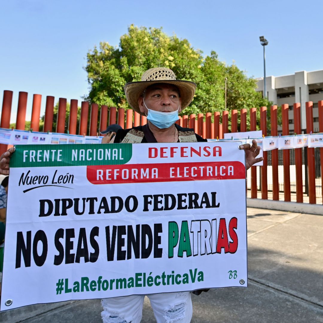 A demonstrator in Mexico City holds a sign in favor of President Andres Manuel Lopez Obrador's proposed electricity reform outside the building housing Mexico's Chamber of Deputies on April 17, 2022, as lawmakers hold a vote on the legislation. 