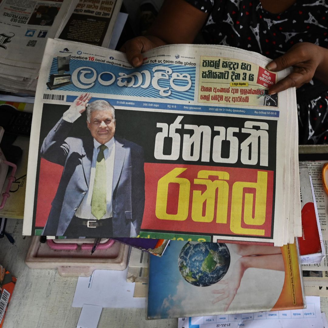 A vendor holds a newspaper with Sri Lanka's President-elect Ranil Wickramasinghe on the front page at a newsstand in Colombo on July 21, 2022. The six-time prime minister was sworn in as president later that day.