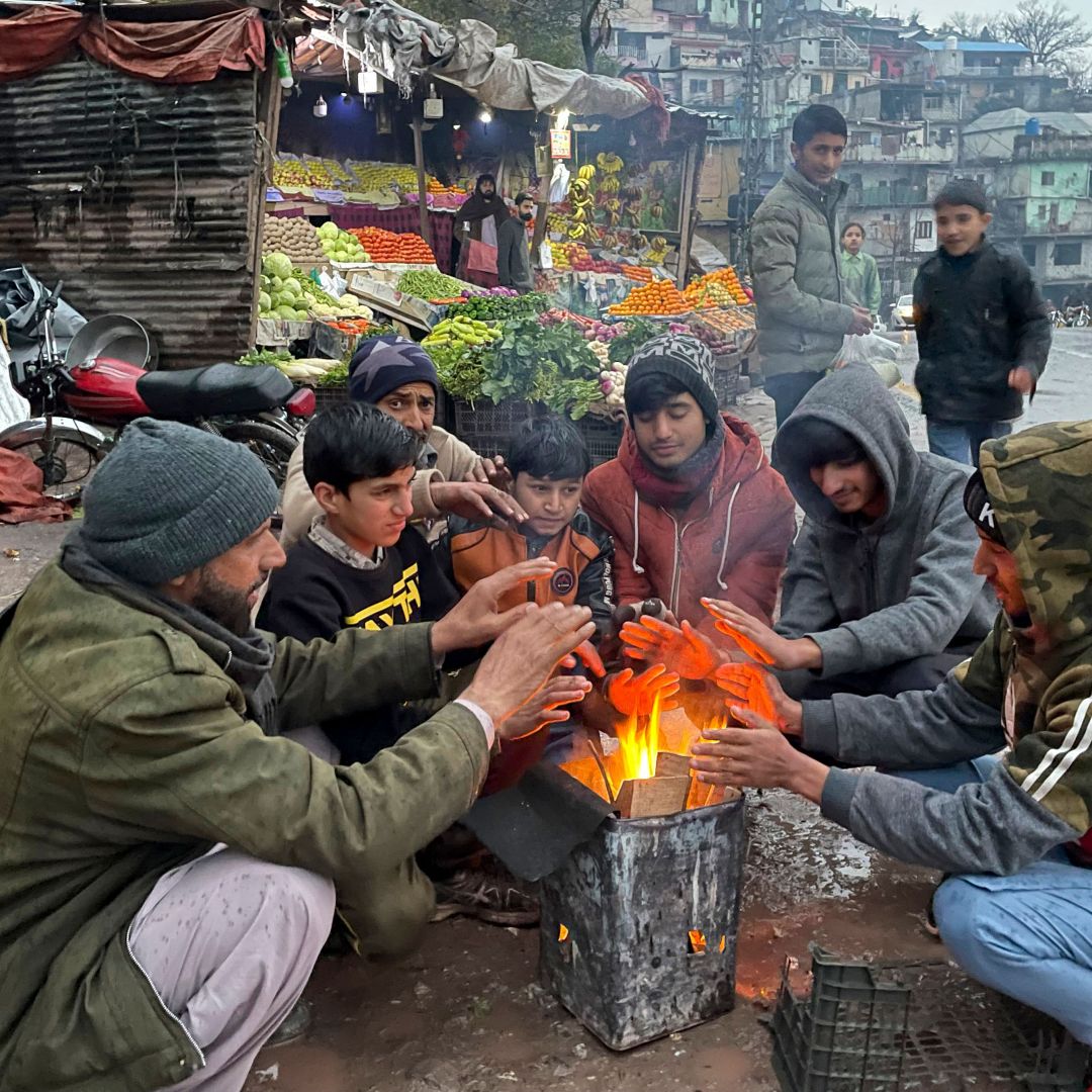 Vendors at a market warm themselves around a bonfire in Muzaffarabad, Pakistan, during a nationwide power outage on Jan. 23, 2023.