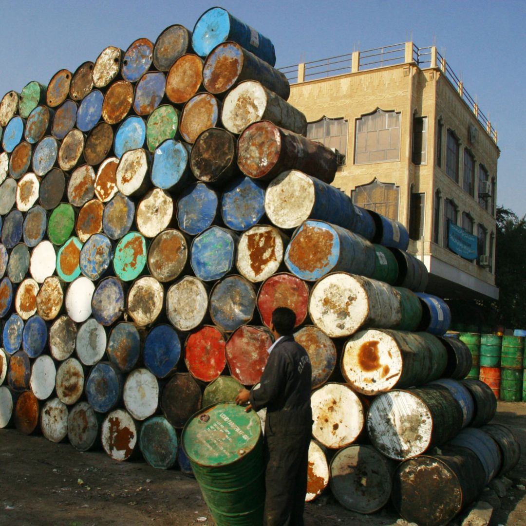 A worker surveys a stack of empty oil drums as he brings another to add to it at a warehouse in Baghdad, Iraq, on Jan. 6, 2004.