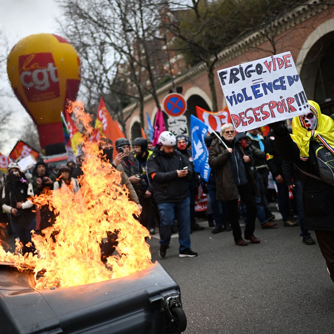 A protestor holds a placard that reads ''Empty Fridge Equals Violence of Dispair'' near a pile of burning trash during a demonstration in Paris, France, against the government's proposed pension reform on March 11, 2023. A protestor holds a placard that reads ''Empty Fridge Equals Violence of Dispair'' near a pile of burning trash during a demonstration in Paris, France, against the government's proposed pension reform on March 11, 2023.