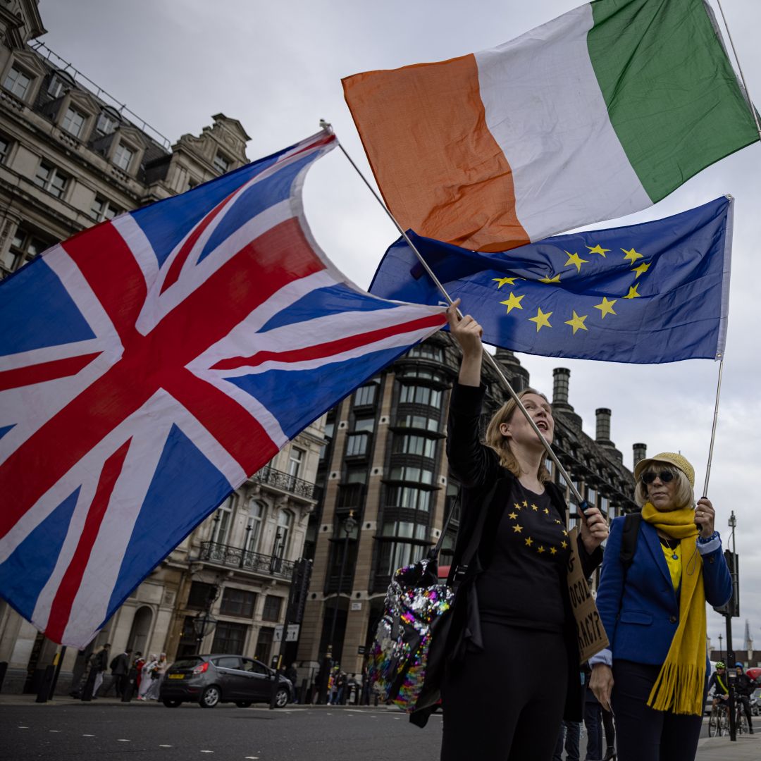 Anti-Brexit protesters wave the flags of the United Kingdom, Ireland and the European Union outside the U.K. Parliament building in London on Oct. 13, 2021. 