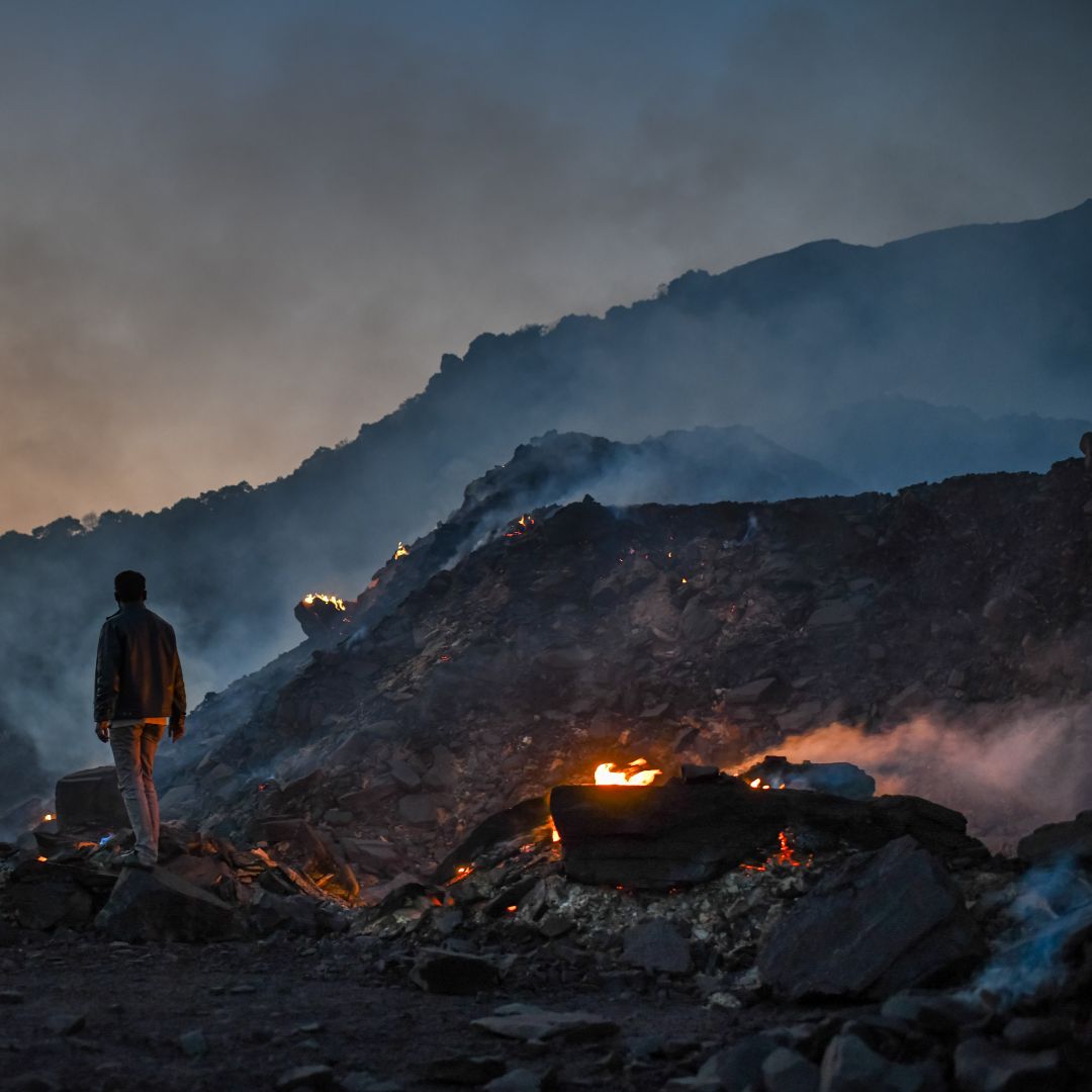 A man stands near burning waste at a coal mine in Sonbhadra, India, on Nov. 22, 2021. High oil and gas prices amid the war in Ukraine risks making India, the world’s second-largest coal consumer, even more reliant on the cheapest (and dirtiest) fossil fuel.