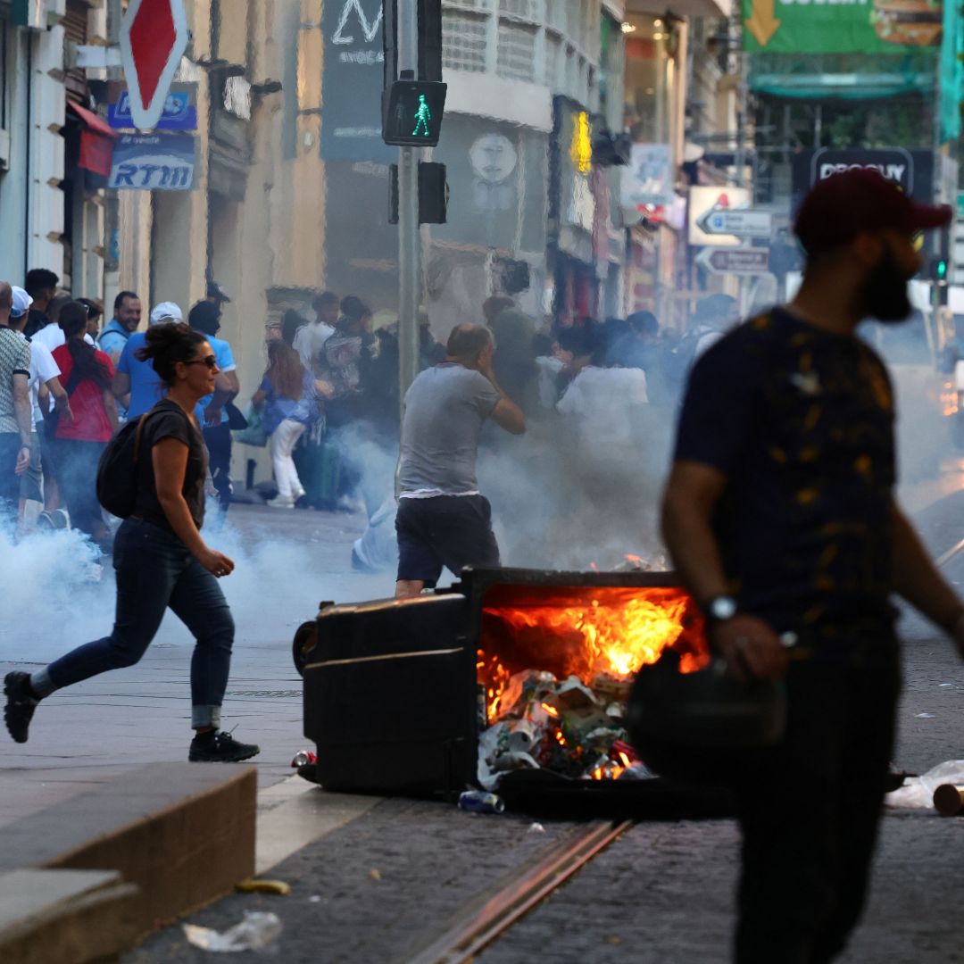 Protesters run from launched tear gas canisters during clashes with police in Marseille, southern France, on July 1, 2023, after a fourth consecutive night of rioting over the killing of a teenager by police.