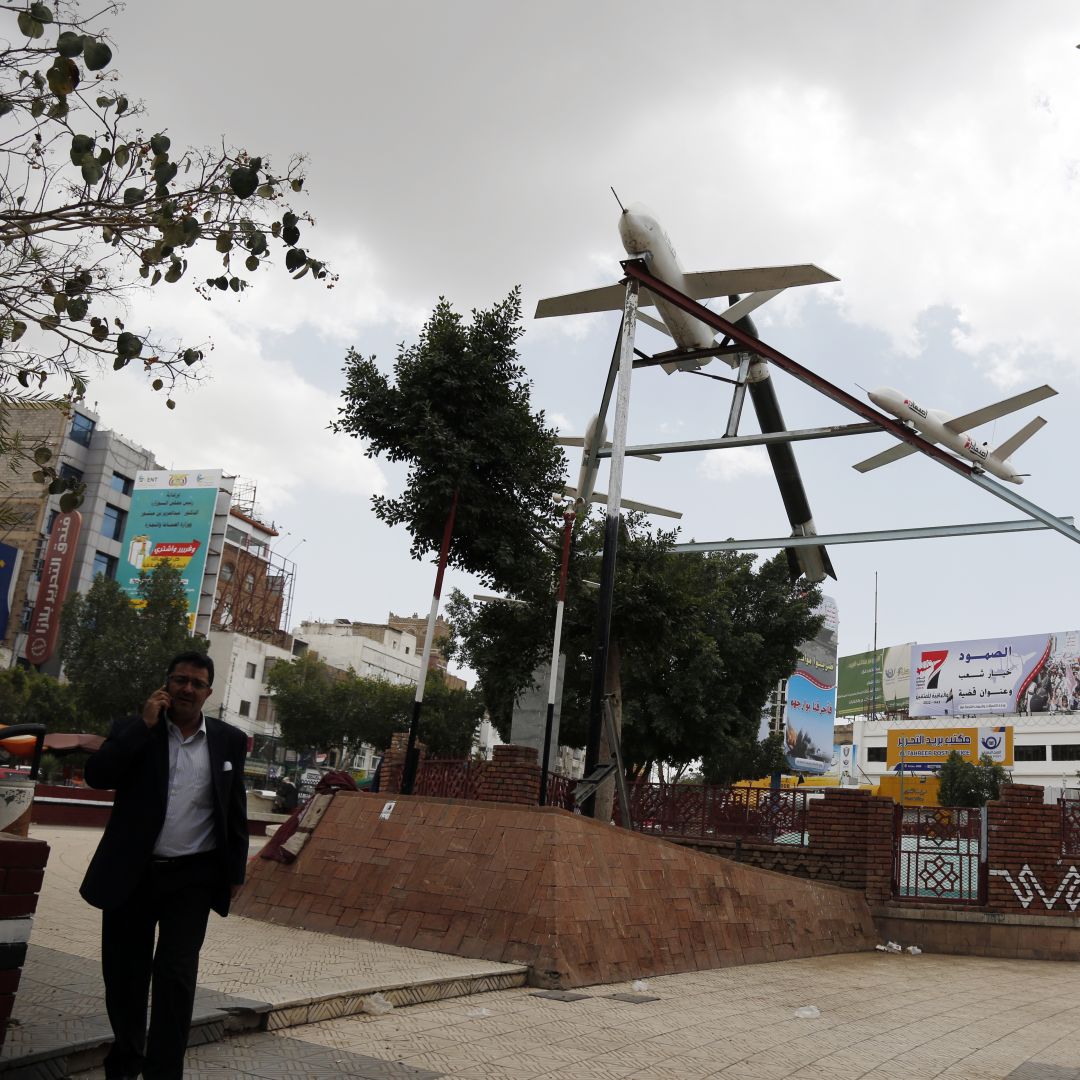 A photo taken in Sanaa, Yemen, on March 21, 2022, shows people walking under mock drones and missiles set up by supporters of the country's Iran-aligned Houthi movement, which earlier conducted attacks against Saudi energy facilities.