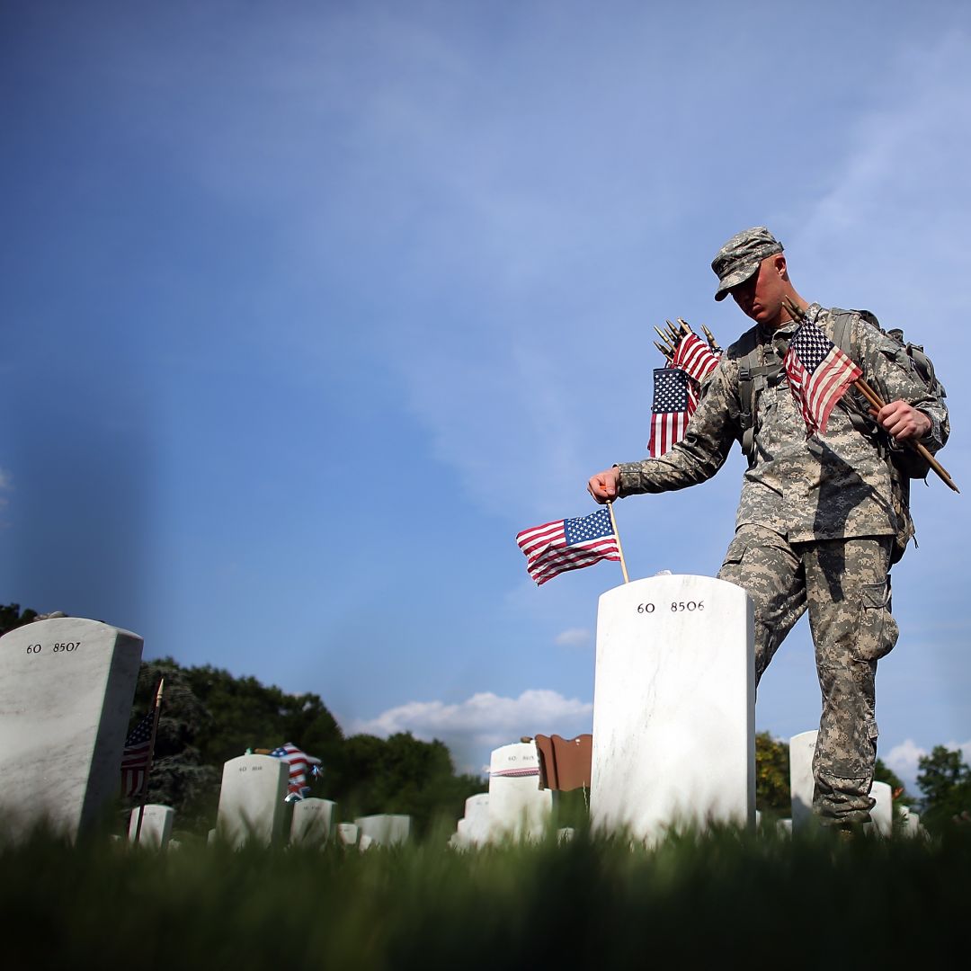 A soldier places flags at the gravesites of U.S. military members buried at the Arlington National Cemetery in Virginia on May 24, 2012. 