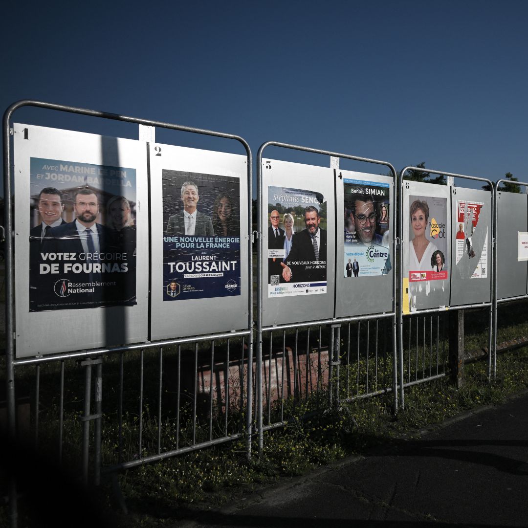 A man walks past campaign posters for France's upcoming legislative elections in Parempuyre, southwestern France, on June 25, 2024.
