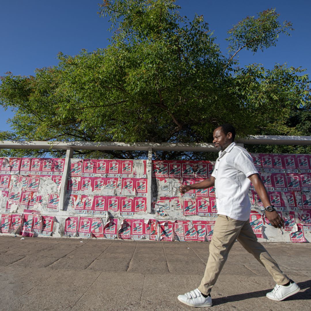 A man in Maputo walks past a wall covered with electoral posters in support of Daniel Chapo, the ruling party candidate in Mozambique’s presidential election, on Oct. 4, 2024. 