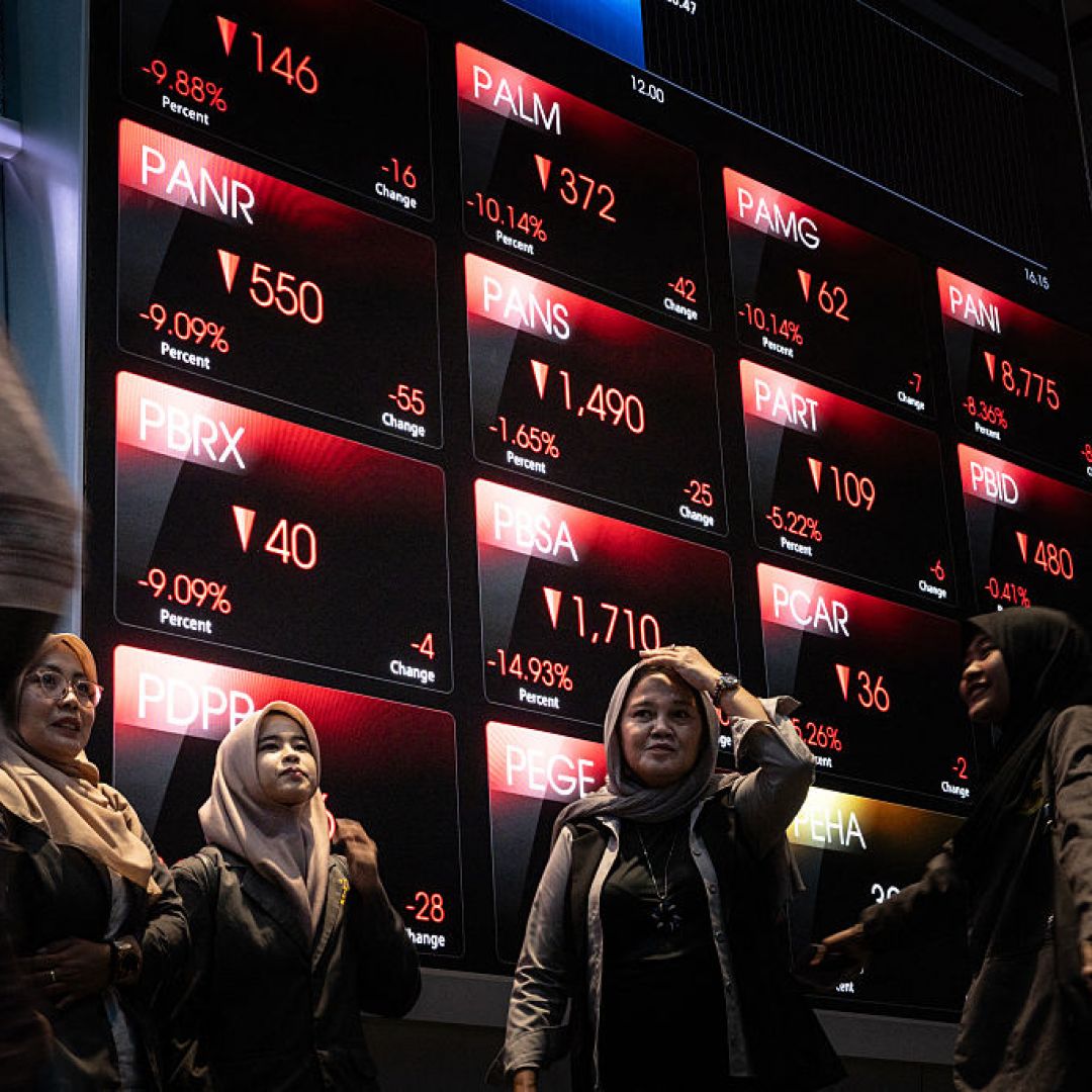 Visitors take pictures in front of an electronic board displaying falling stock prices at the Indonesia Stock Exchange in Jakarta on Jan. 29, 2026.