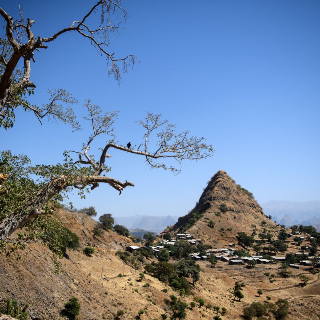 A photograph shows a village below a prominent hill in the Semien Mountains near Gondar, Ethiopia.