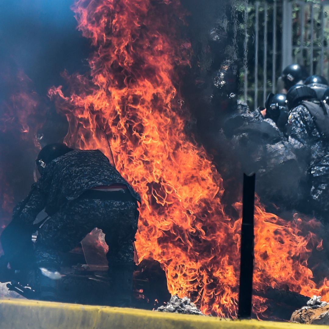 Police officers engulfed in flames from an incendiary device during protests in Caracas on July 30.