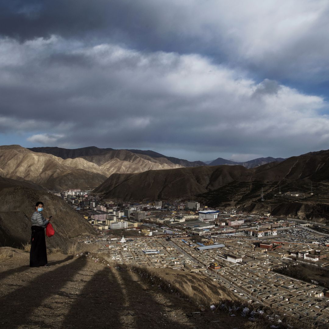 A Tibetan Buddhist woman stands on a hill overlooking the Labrang Monastery on March 2, 2018, in Gansu, China, the country's poorest province.