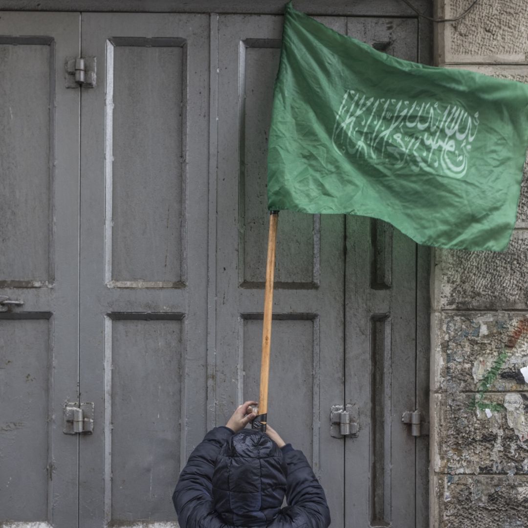 A child tapes a stick holding a Hamas flag during a demonstration in support of Palestinian resistance in the West Bank city of Ramallah, on Jan. 12, 2024. 