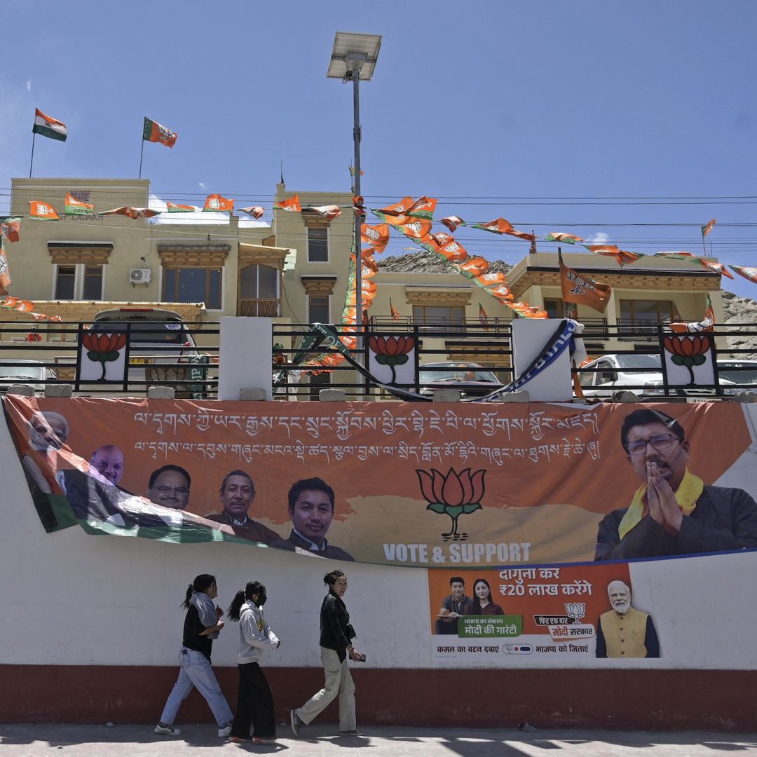 People walk past campaign posters for the ruling Bharatiya Janata Party (BJP) outside the party's office in Leh, India, on May 17, 2024, during the country's ongoing general election.