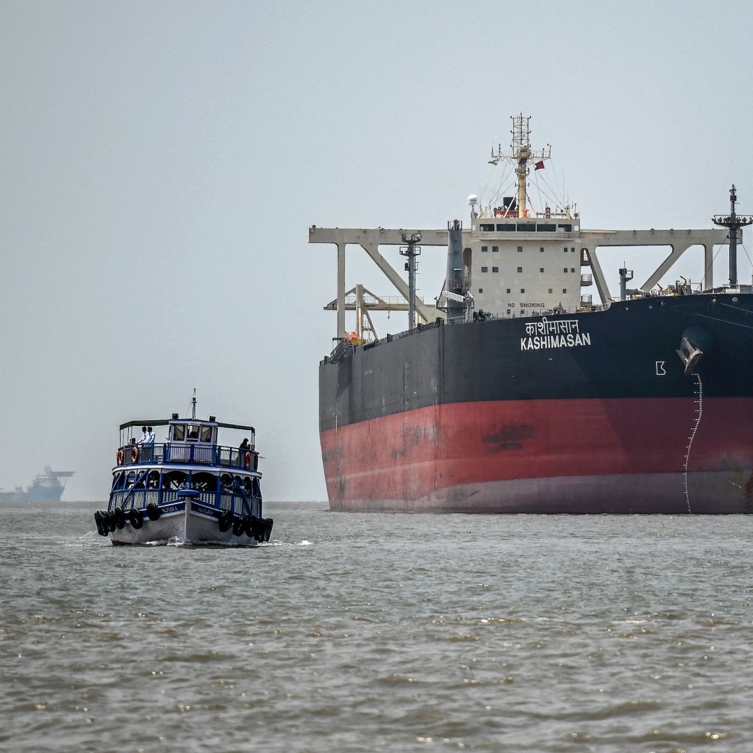 A passenger boat sails past the Indian-flagged oil tanker Kashimasan, which is docked near an offloading terminal at Butcher Island (also known as Jawahar Dweep) off the coast of Mumbai, India, on April 1, 2026.
