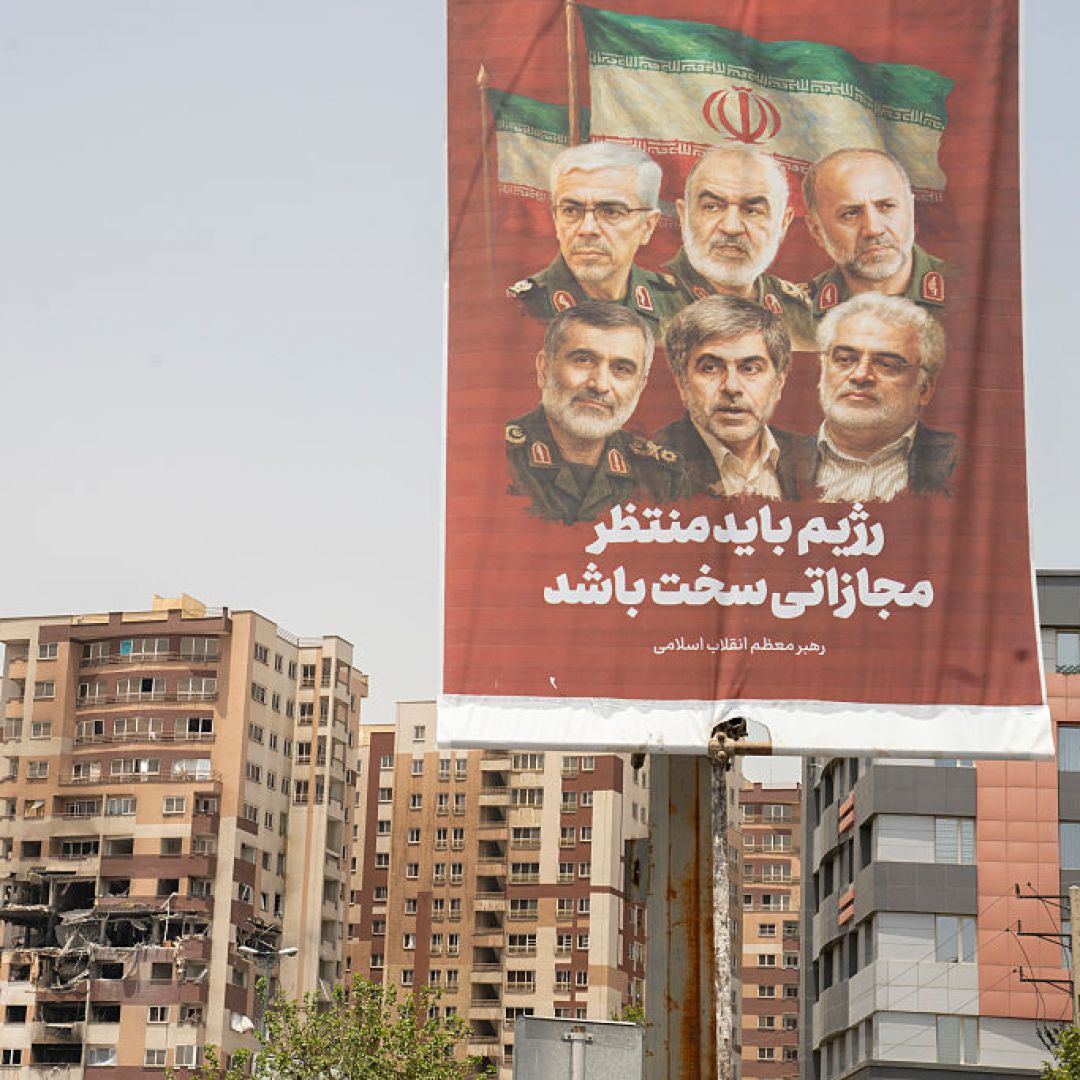 A photo taken in Tehran, Iran, on June 26, 2025, shows an Iranian political banner hanging near the remains of a residential building struck by an Israeli attack. 