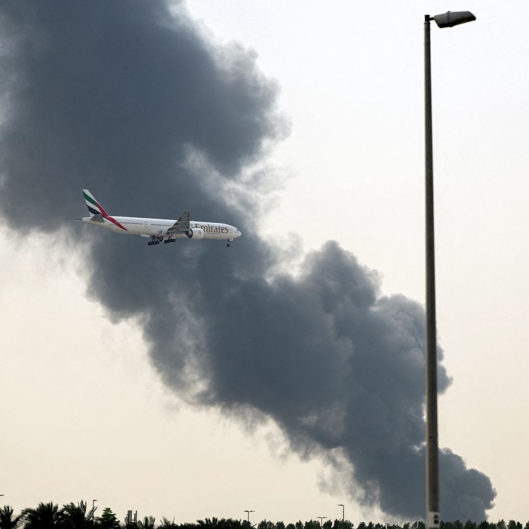 An Emirates Boeing 777 aircraft prepares for landing as a smoke plume rises from an ongoing fire near Dubai International Airport in Dubai on March 16.