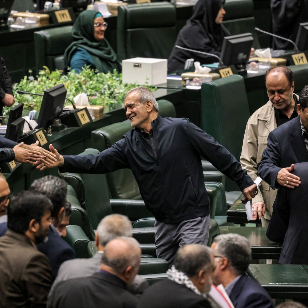 Iran's President Masoud Pezeshkian (C) greets parliament members after giving an address during a session to approve his new Cabinet appointments in Tehran on Aug. 21, 2024.