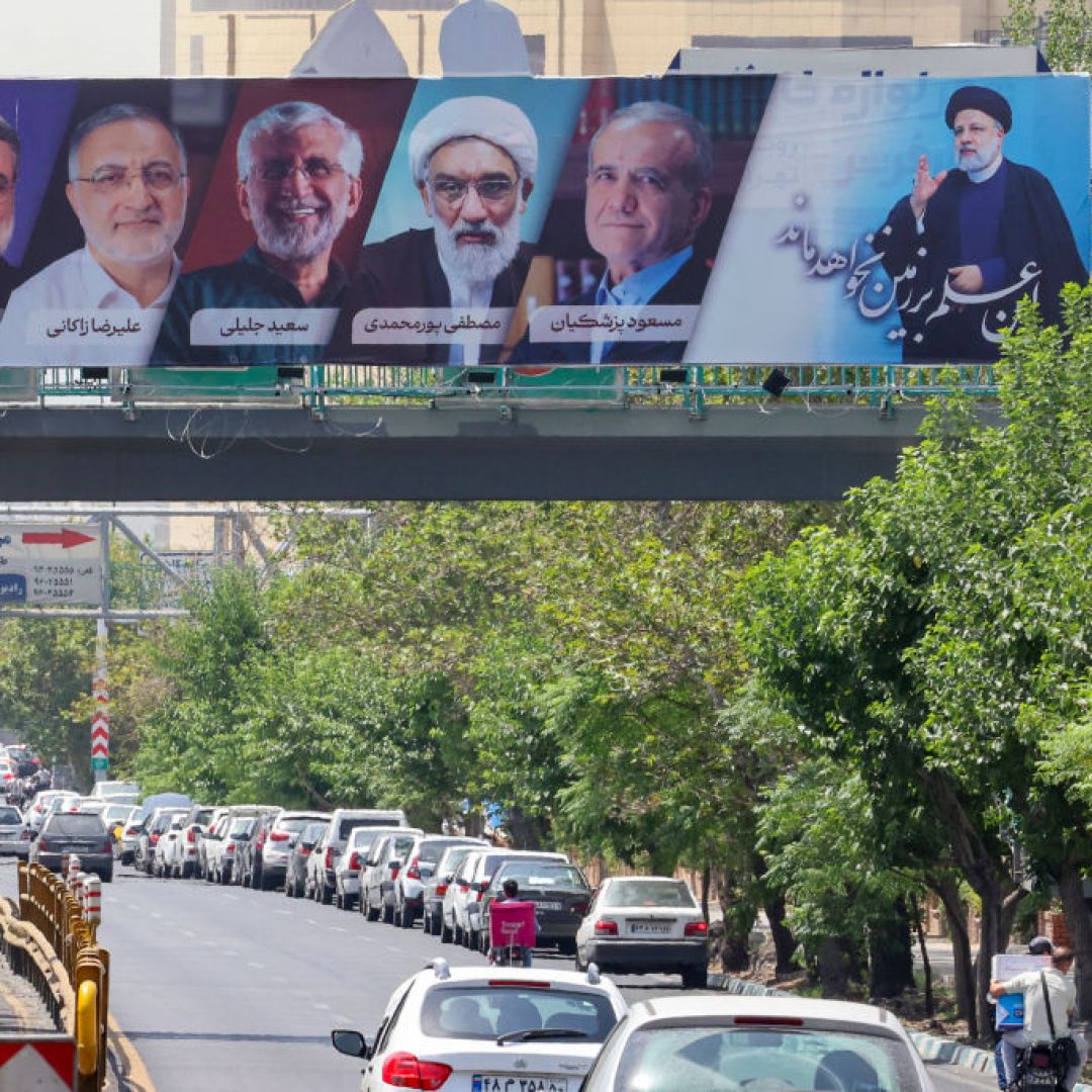 A billboard displaying the faces of the six candidates in Iran's 2024 presidential election with July 5 runoff winner Masoud Pezeshkian at second from right.