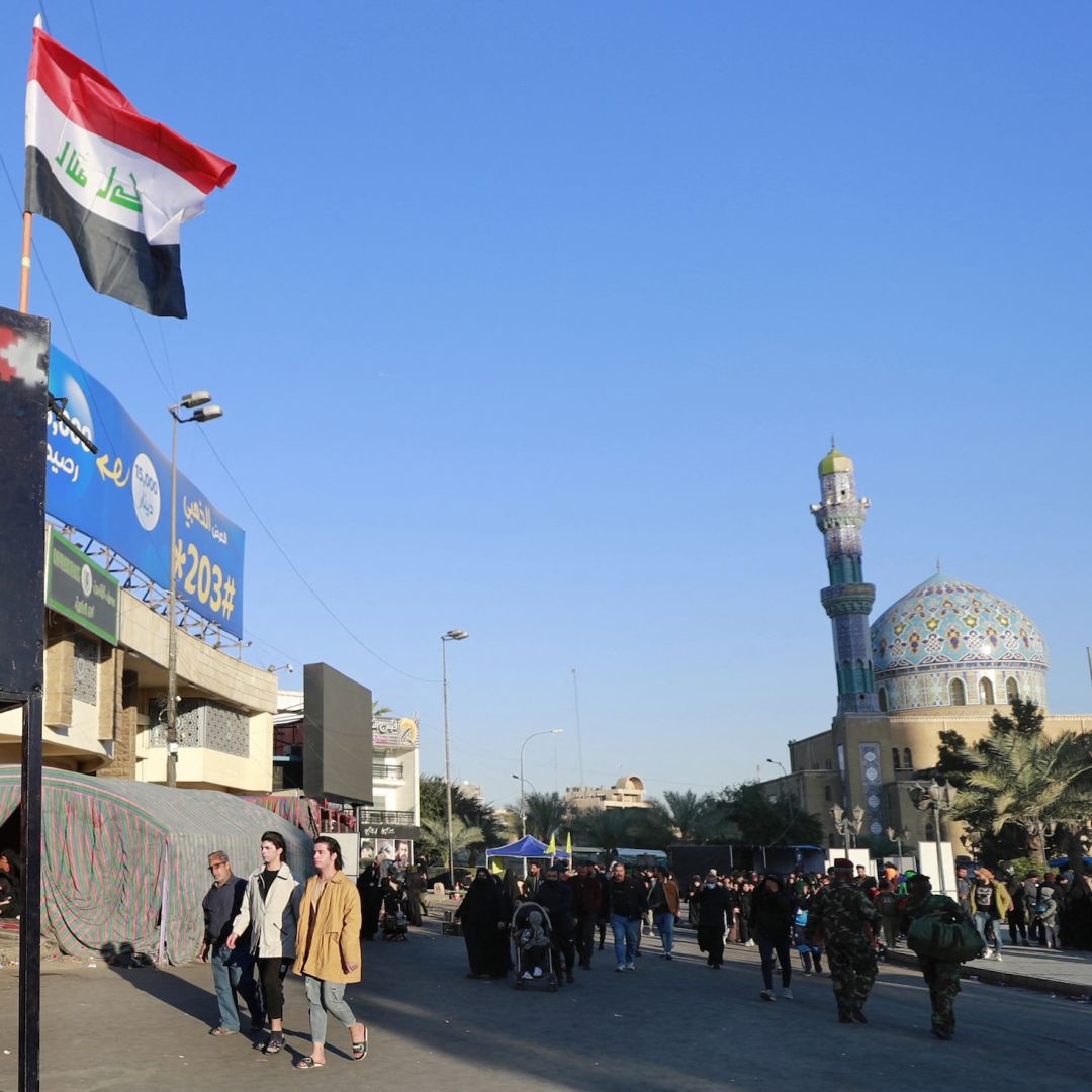 A member of the Iraqi security forces stands guard next to a national flag as pilgrims march from the center of Baghdad toward the shrine of Imam Moussa al-Kadhim, the seventh of 12 revered imams in Shiite Islam, during an annual religious commemoration on Feb. 16, 2023.