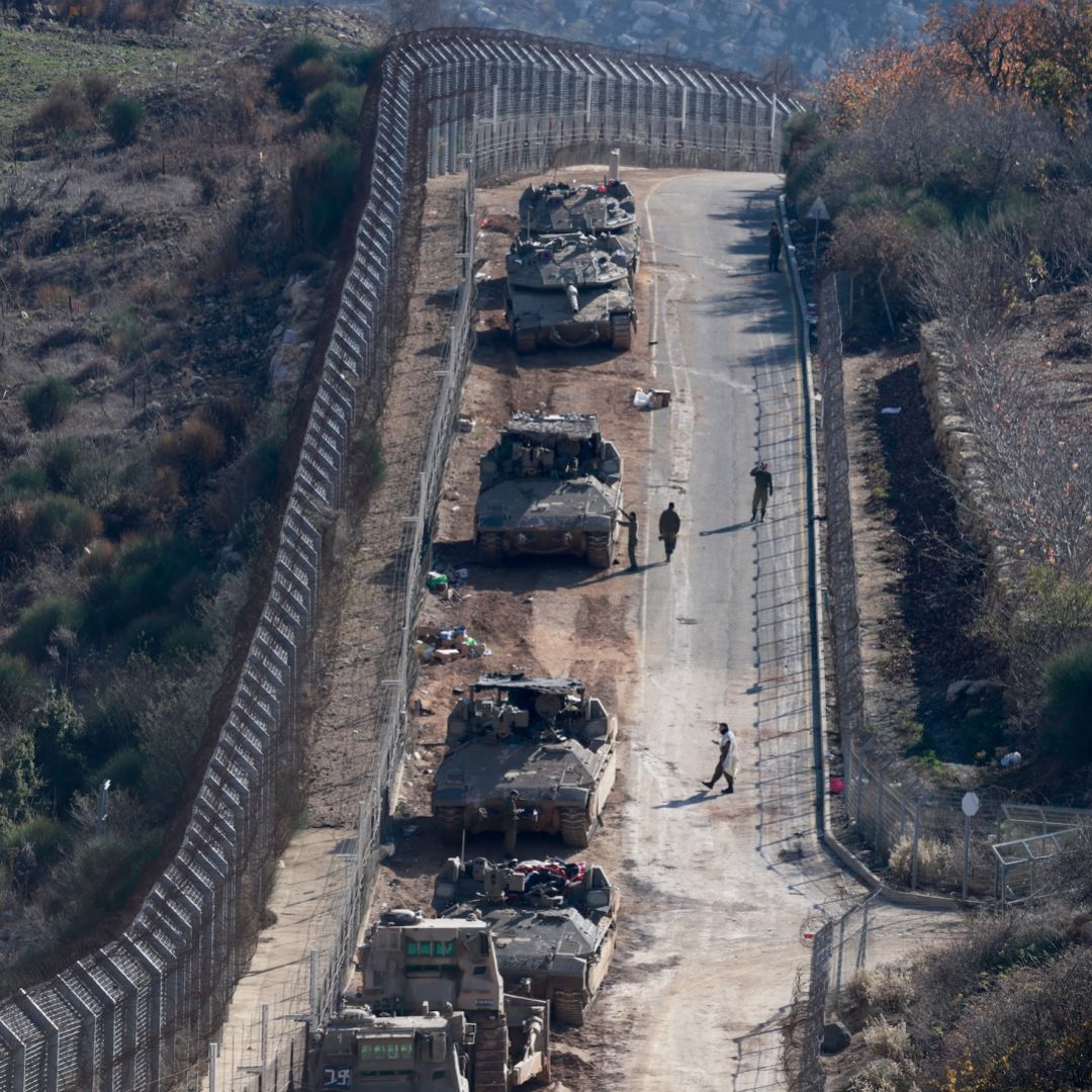 Israeli tanks and armored vehicles line up the area outside the Druze village of Majdal Shams on the fence with the buffer zone that separates the Israeli-annexed Golan Heights from the rest of Syria on Dec. 9, 2024.