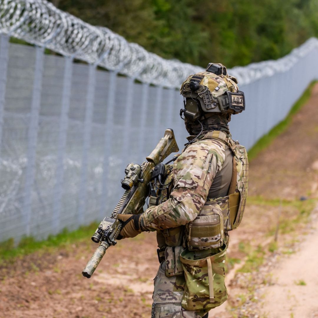 A Latvian border guard patrols along the fence at the Belarusian border near Krivanda, eastern Latvia, on Aug. 8, 2023.
