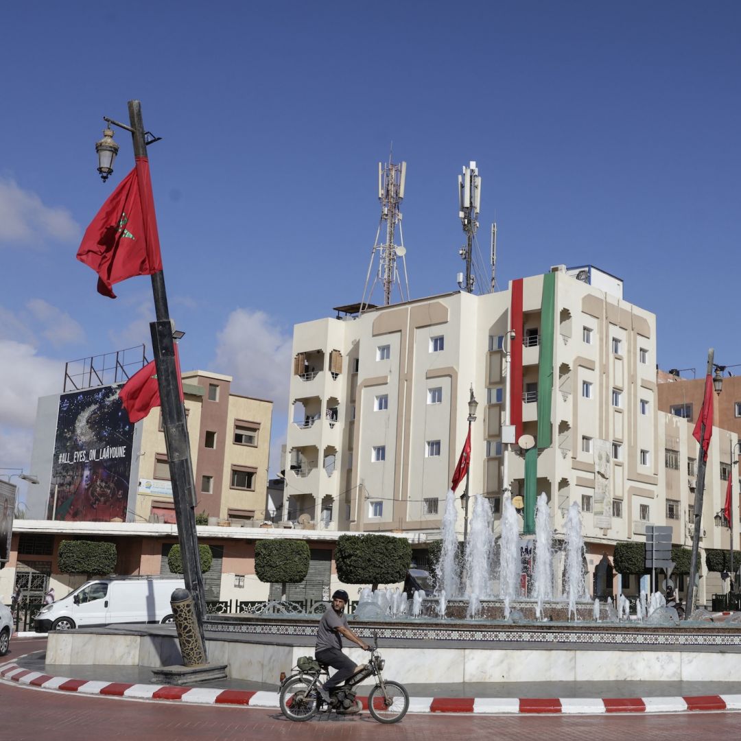 A man rides past a roundabout adorned with Moroccan national flags in Laayoune, the main city of Moroccan-controlled Western Sahara, on Nov. 7, 2025.