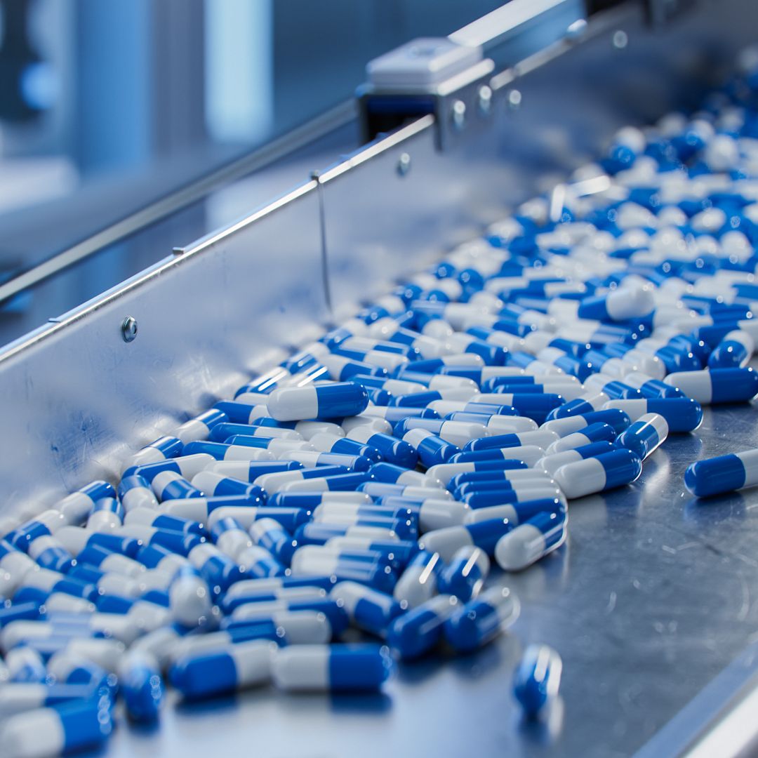 A stock photo shows blue capsules on a conveyor at a pharmaceutical factory. A stock photo shows blue capsules on a conveyor at a pharmaceutical factory.