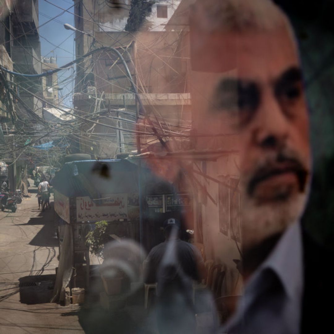 People are reflected in a window displaying a poster of Hamas leader Yahya Sinwar in the Palestinian camp of Bourj al-Barajneh on Aug. 8, 2024, in Beirut, Lebanon. 