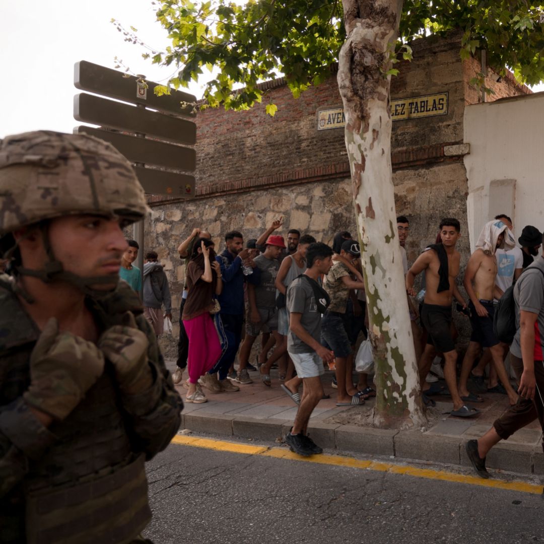 A Spanish soldier escorts a group of migrants on their way back towards the Moroccan border, following their illegal crossing into the Spanish enclave of Ceuta, on Aug. 1, 2026.
