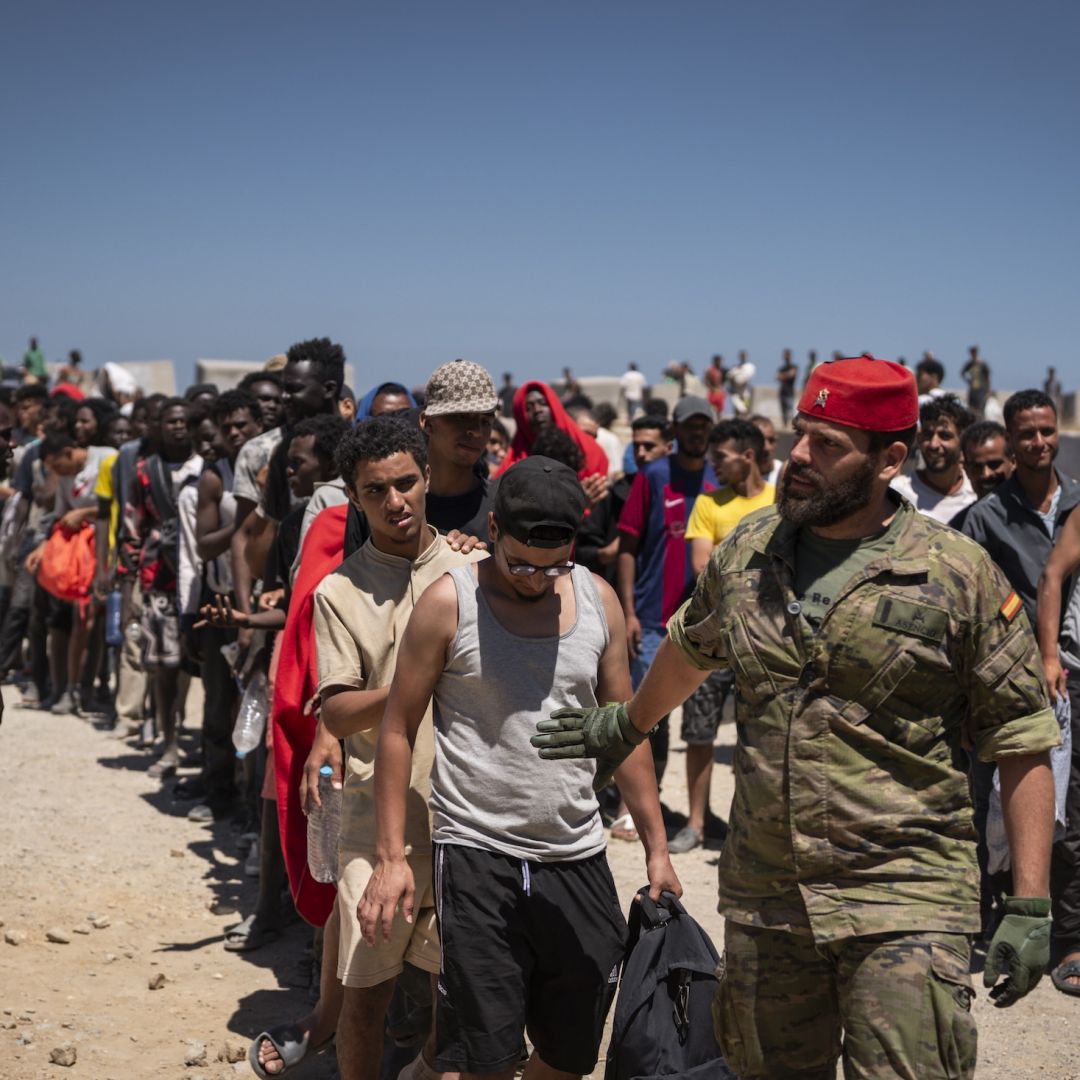 Migrants wait to receive water on a beach in the North African Spanish enclave of Ceuta on Aug. 2, 2026.