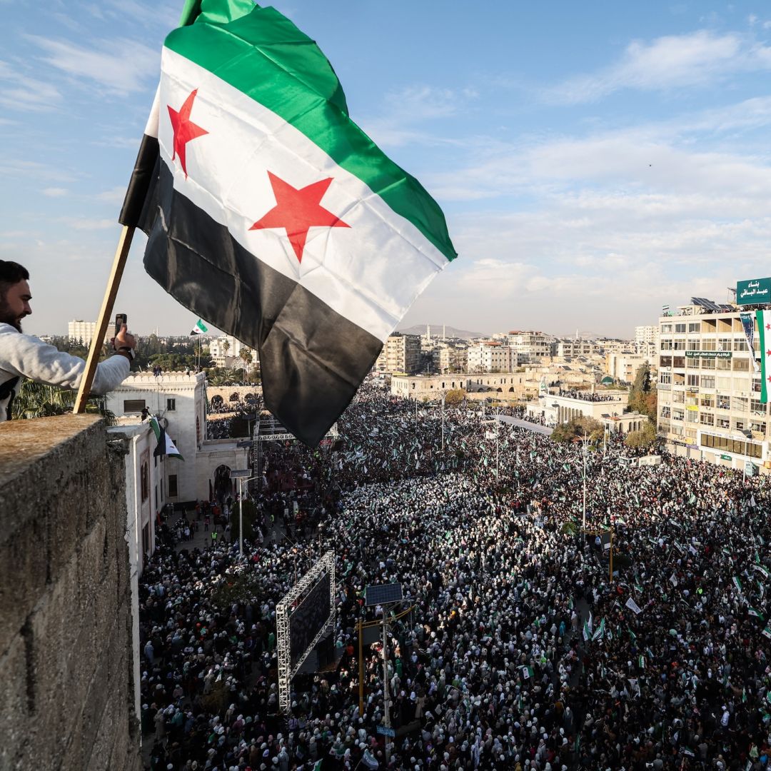 A Syrian flag flutters above crowds gathering in central Hama, Syria, during celebrations on Dec. 5, 2025, marking one year since the fall of former President Bashar al Assad's regime. A Syrian flag flutters above crowds gathering in central Hama, Syria, during celebrations on Dec. 5, 2025, marking one year since the fall of former President Bashar al Assad's regime.
