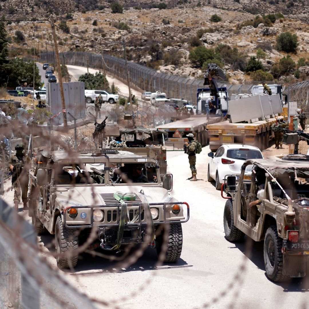 Israeli military vehicles drive along a border fence, near the town of Majdal Shams, in the Israeli-annexed Golan Heights, on July 17, 2025. 