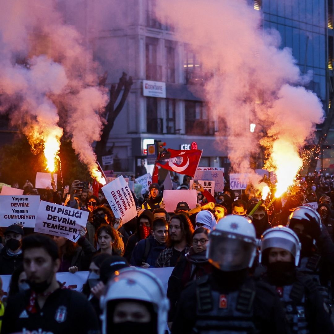 Escorted by riot police, students burn flares on March 24, 2025, as they march along the streets of Istanbul, Turkey, in support of the city's mayor after he was arrested on corruption charges. 