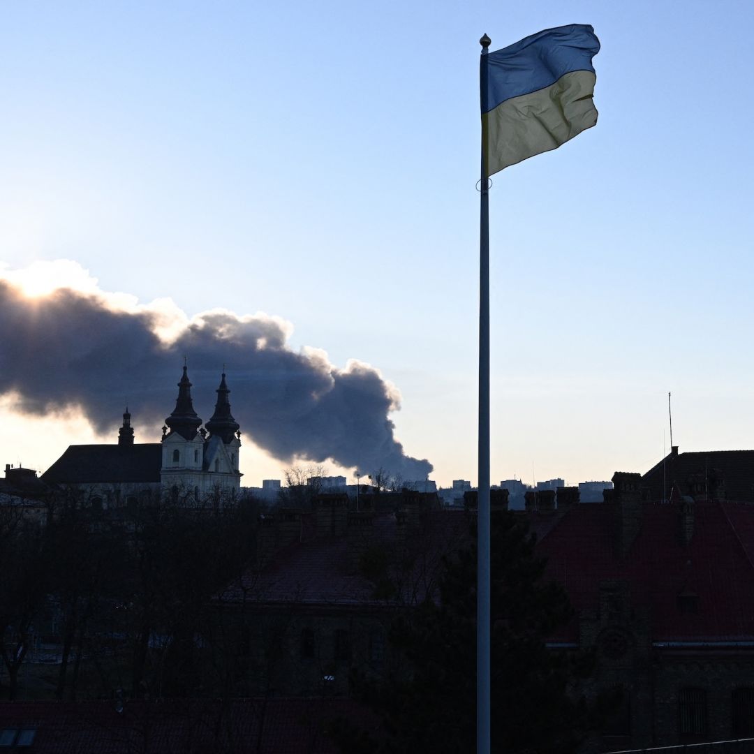 Smoke rises in the background as a Ukrainian flag flutters in the wind following a mass overnight Russian drone and missile attacks, in the western Ukrainian city of Lviv on Nov. 19, 2025. 
