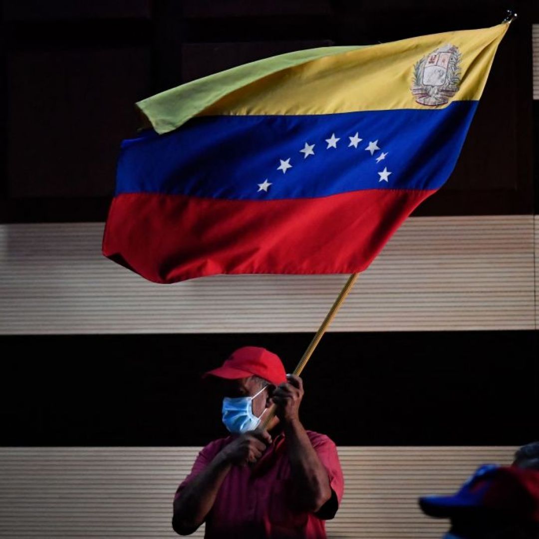 A supporter of the ruling United Socialist Party of Venezuela waves the flag of Venezuela on Jan. 10, 2022, in Barinas, Venezuela. The four major political parties that comprise Venezuela's opposition coalition will vote Dec. 29 on a motion to eliminate the country's interim government. A supporter of the ruling United Socialist Party of Venezuela waves the flag of Venezuela on Jan. 10, 2022, in Barinas, Venezuela.