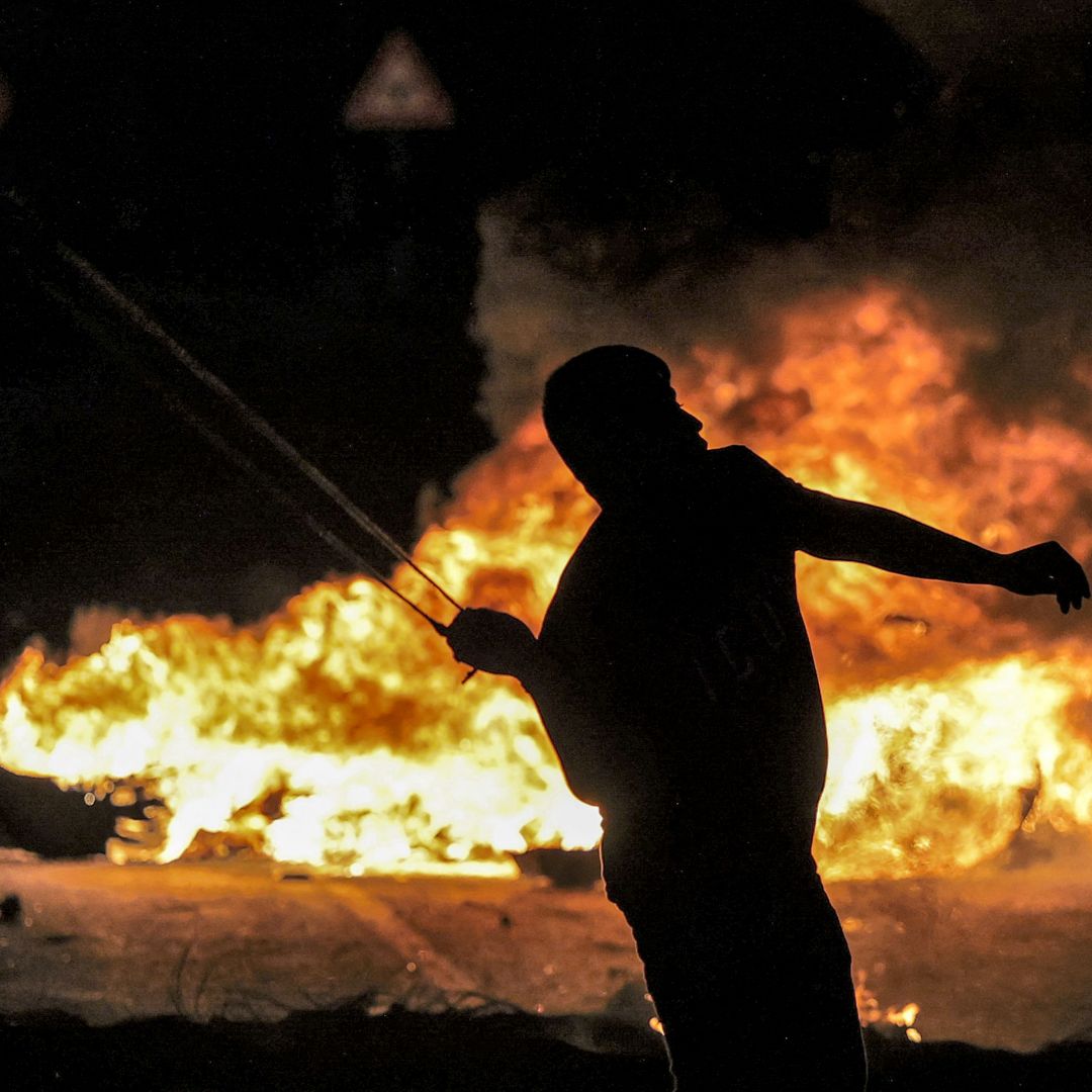 A Palestinian youth throws a rock with a slingshot at Israeli security forces during Oct. 3, 2022, clashes at the northern entrance of the city of Ramallah in the West Bank. The recent sustained increase in Palestinian militant violence highlights both the short-and long-term threat West Bank militancy poses to Israeli-Palestinian security. A Palestinian youth throws a rock with a slingshot at Israeli security forces during Oct. 3, 2022, clashes at the northern entrance of the city of Ramallah in the West Bank.