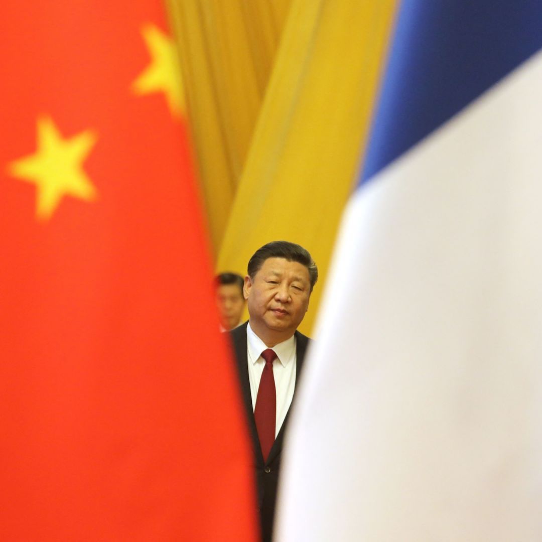 Chinese President Xi Jinping is seen between the Chinese and French national flags in Beijing on Jan. 9, 2018. 