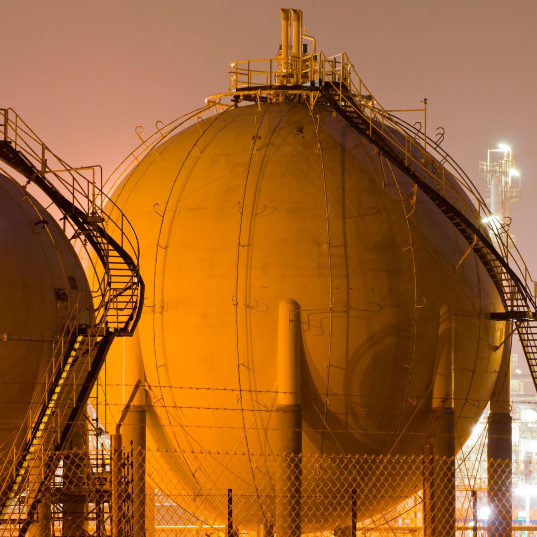 Storage tanks for liquefied natural gas sit in a large oil-refinery plant