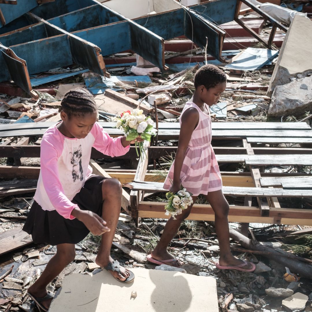 Girls collect artificial flowers from the rubble of a building destroyed by Cyclone Idai at Sacred Heart Catholic Church in Beira, Mozambique, on March 24, 2019.