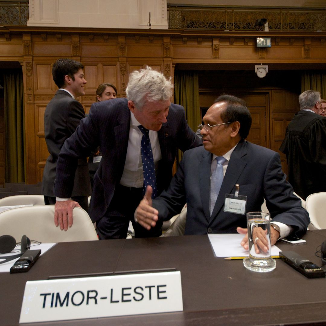 Timor-Leste's Foreign Affairs minister Jose Luis Gutierrez (R) speaks with Australian lawyer Bernard Collaery (L) during a session of the International Court of Justice in 2014. Collaery faces prosecution in Australia for disclosing information about the country's intelligence services in a case worthy of a spy novel.