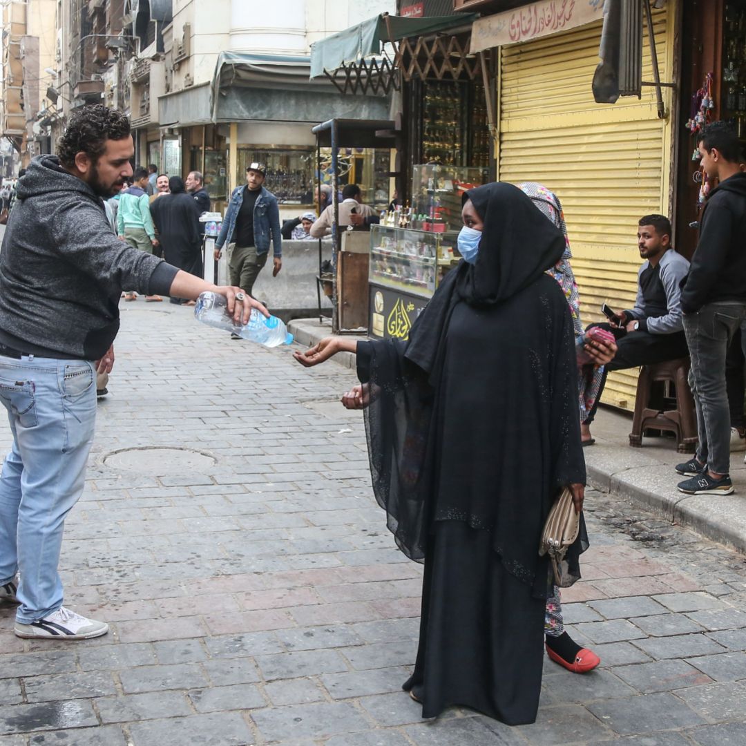A man provides a pedestrian with hand sanitizer as protection against COVID-19 on the historic Al-Moez street in Cairo, Egypt, on March 23, 2020.